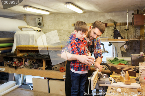 Image of father and son with chisel working at workshop