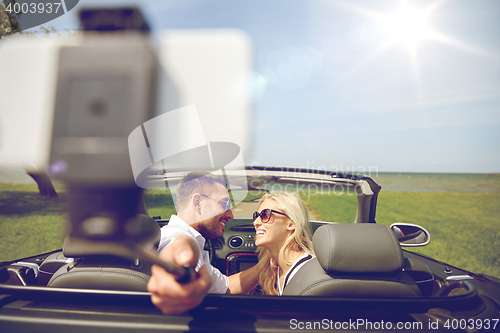 Image of happy couple in car taking selfie with smartphone