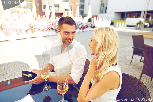 Image of happy couple with wallet paying bill at restaurant