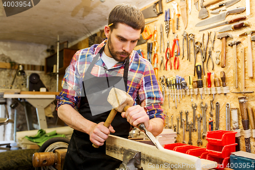 Image of carpenter with wood, hammer and chisel at workshop