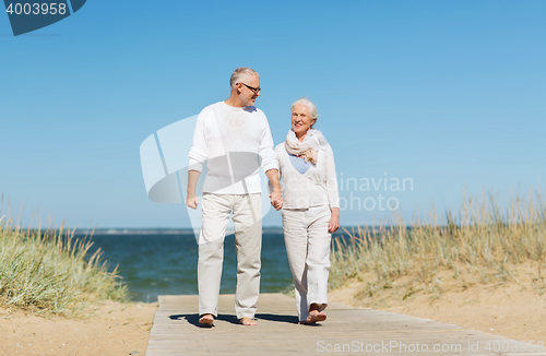Image of happy senior couple holding hands on summer beach