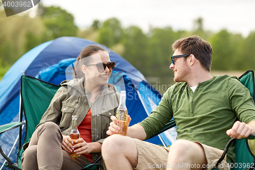 Image of happy couple drinking beer at campsite tent