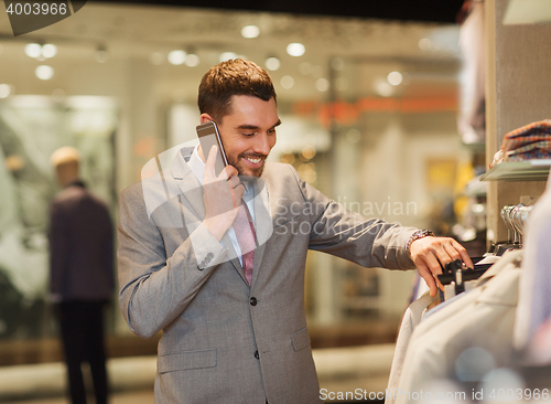 Image of happy man calling on smartphone at clothing store