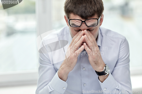 Image of tired businessman with eyeglasses in office