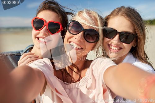 Image of group of smiling women taking selfie on beach