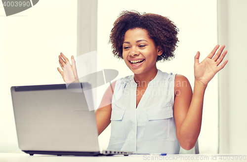 Image of happy african woman with laptop at office