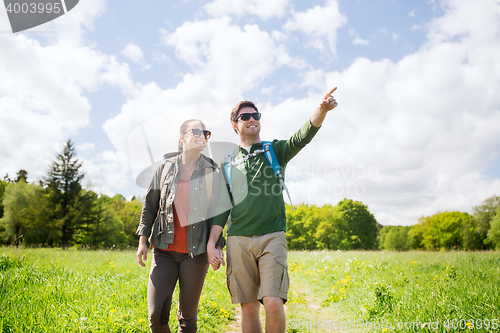 Image of happy couple with backpacks hiking outdoors