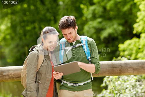 Image of happy couple with backpacks and tablet pc outdoors