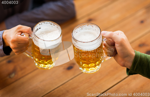 Image of close up of hands with beer mugs at bar or pub