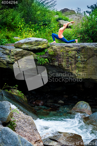 Image of Sporty fit woman practices yoga Anjaneyasana in mountains