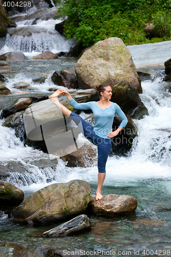 Image of Woman doing Ashtanga Vinyasa Yoga asana outdoors at waterfall