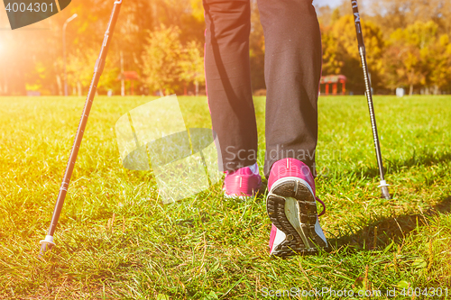 Image of Woman nordic walking outdoors feet close up