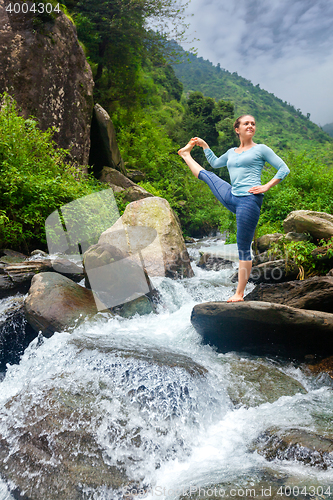 Image of Woman doing Ashtanga Vinyasa Yoga asana outdoors at waterfall