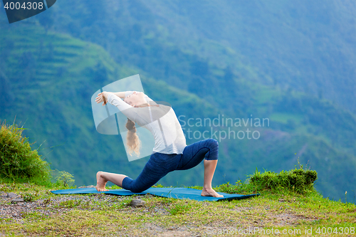 Image of Sporty fit woman practices yoga asana Anjaneyasana in mountains