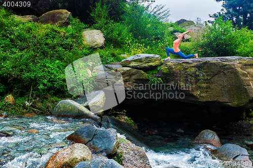 Image of Sporty fit woman practices yoga Anjaneyasana in mountains