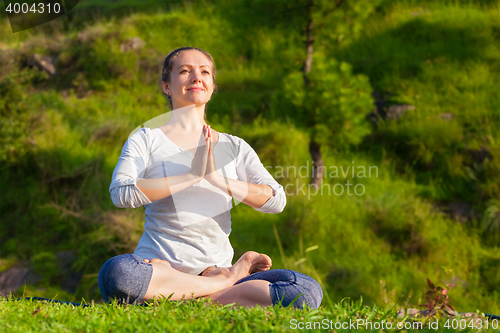 Image of Young sporty fit woman doing yoga Lotus pose oudoors 