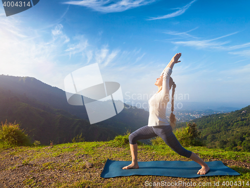 Image of Woman doing yoga asana Virabhadrasana 1 - Warrior pose outdoors