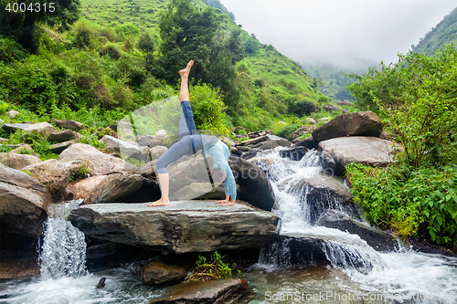 Image of Woman doing yoga asana at waterfall