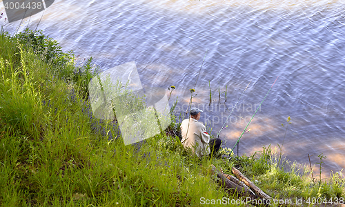 Image of  A fisherman with a fishing rod on the river bank