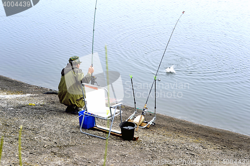 Image of  A fisherman with a fishing rod on the river bank