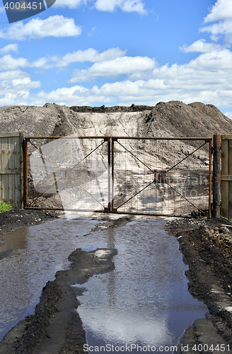 Image of Dirt road, a pool and a lot of stored in the open air ground for a closed fence