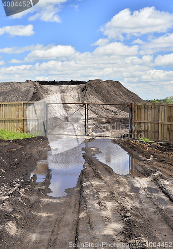 Image of Dirt road, a pool and a lot of stored in the open air ground for a closed fence
