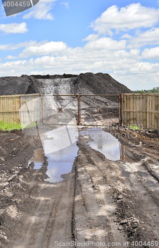 Image of Dirt road, a pool and a lot of stored in the open air ground for a closed fence