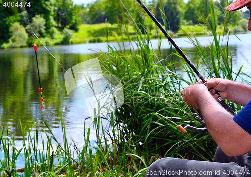 Image of  Close up of guy sitting on bridge and fishing