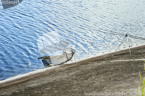 Image of Fish Tank and fishing rod on the shore of the lake on a backgrou