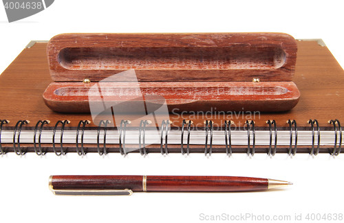 Image of pen in an opened wooden case on notebook