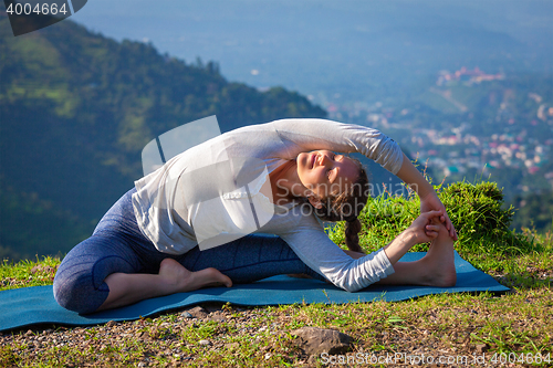 Image of Young sporty fit woman doing Yoga asana parivritta janu sirsasana