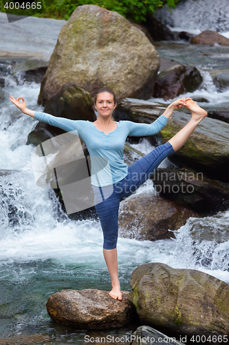 Image of Woman doing Ashtanga Vinyasa Yoga asana outdoors at waterfall