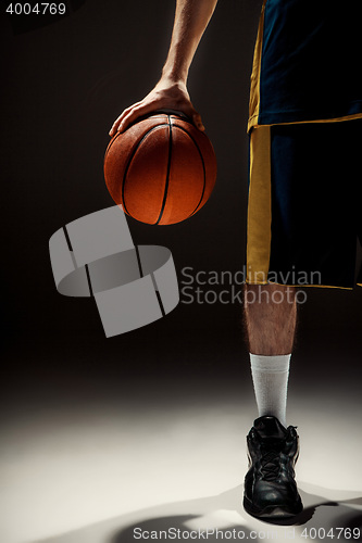 Image of Silhouette view of a basketball player holding basket ball on black background