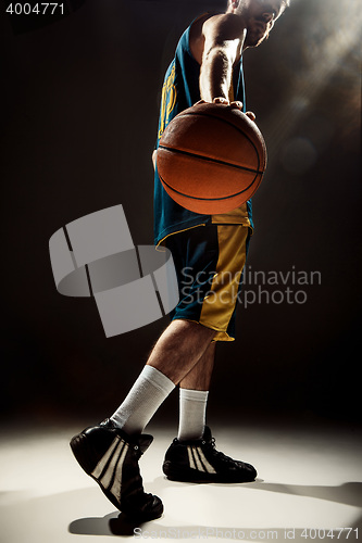Image of Silhouette view of a basketball player holding basket ball on black background