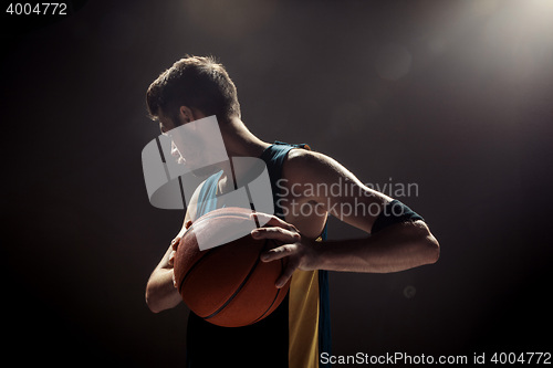 Image of Silhouette view of a basketball player holding basket ball on black background