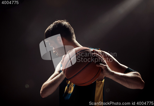 Image of Silhouette view of a basketball player holding basket ball on black background