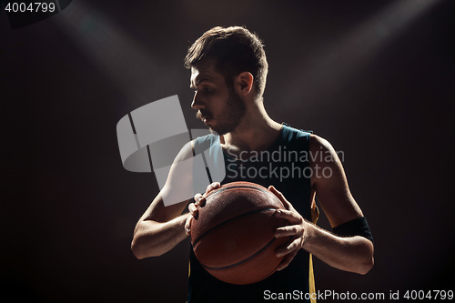 Image of Silhouette view of a basketball player holding basket ball on black background