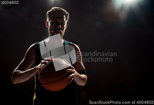 Image of Silhouette view of a basketball player holding basket ball on black background