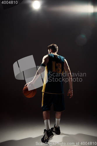 Image of Silhouette view of a basketball player holding basket ball on black background