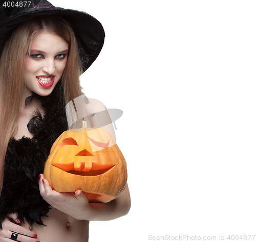 Image of Woman in witch costume opens carved Halloween pumpkin