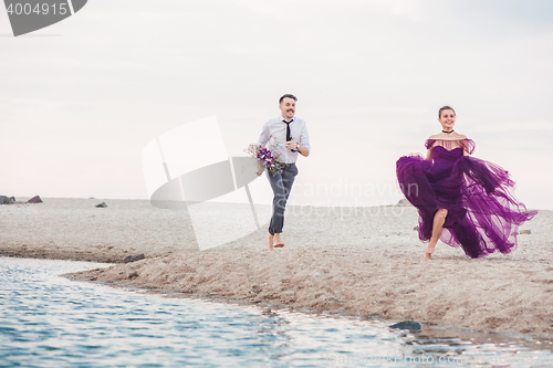 Image of Young romantic couple running on the beach of sea