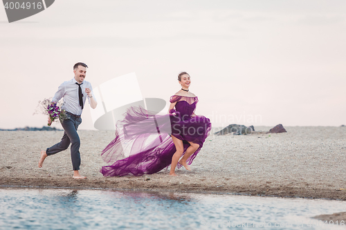 Image of Young romantic couple running on the beach of sea