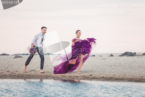 Image of Young romantic couple running on the beach of sea