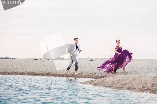 Image of Young romantic couple running on the beach of sea