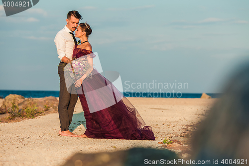 Image of Young romantic couple relaxing on the beach watching the sunset