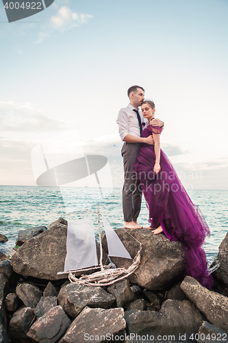 Image of Young romantic couple relaxing on the beach watching the sunset