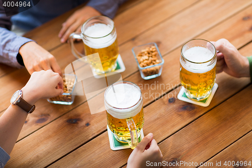 Image of close up of hands with beer mugs at bar or pub