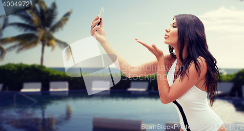 Image of young woman taking selfie with smartphone