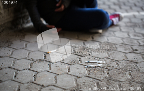 Image of close up of addict woman and drug syringes