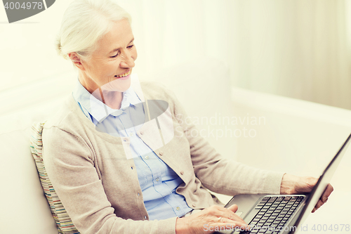 Image of happy senior woman with laptop at home